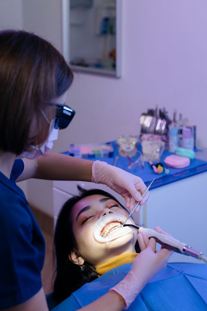 services-03 Dentist examining patient's teeth with tools in a modern clinic setting.