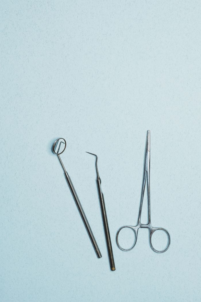 Crafting Captivating Headlines: Your awesome post title goes here Stainless steel dental instruments arranged on a blue surface, featuring a mirror, excavator, and plier.